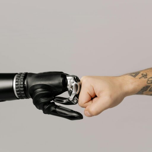 Close-up of a human fist bumping a prosthetic hand, symbolizing technology and human connection.